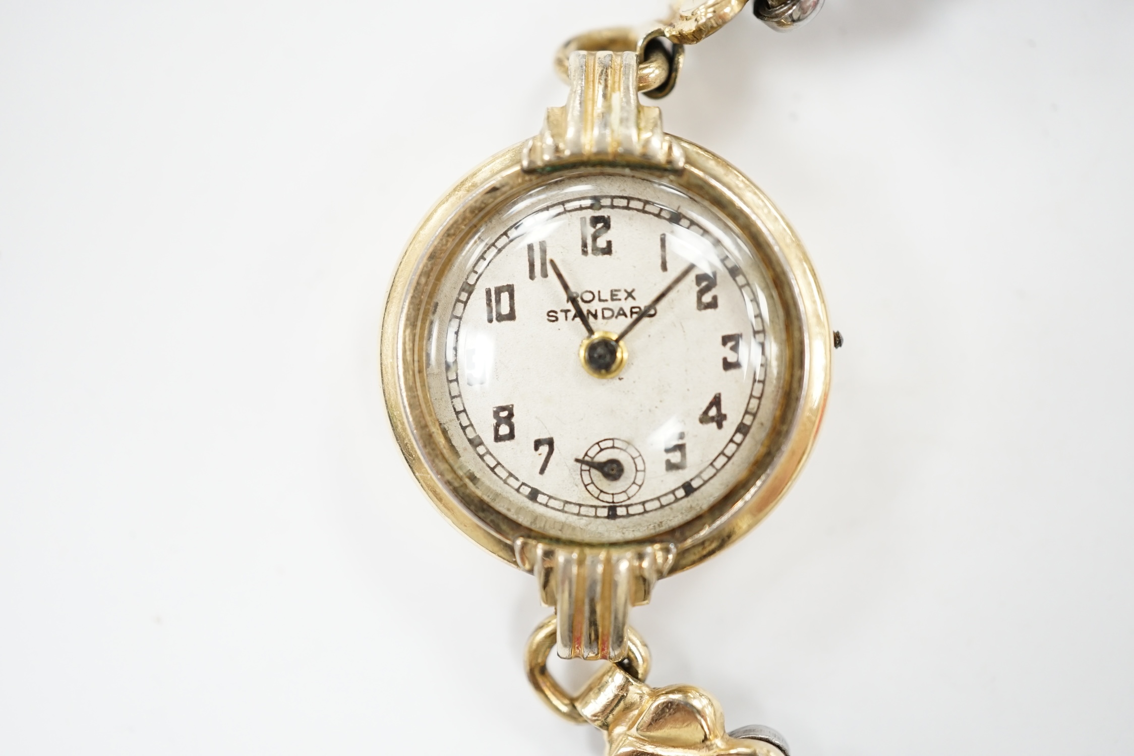 A lady's gilt metal manual wind wrist watch, the dial inscribed 'Rolex Standard', movement unsigned and no winding crown, on an associated flexible link bracelet. Condition - poor